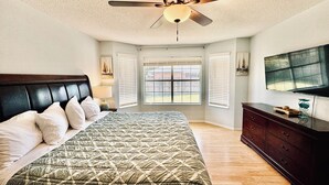 A bedroom with a bed, a ceiling fan, a dresser, and a TV. - Large home near the ocean, sleeps 1-11 guest! (Navarre)