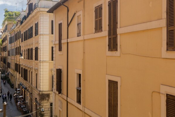 Gelbe Häuser mit Fensterläden, eine Kopfsteinpflasterstraße und Außenbestuhlung.