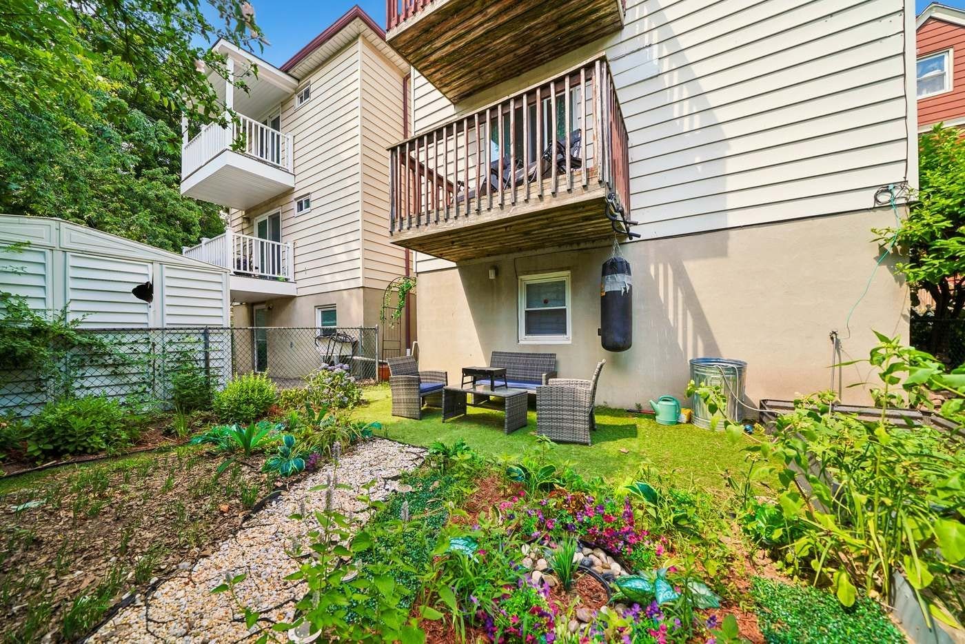 Un immeuble résidentiel doté d’un balcon, d’un espace extérieur aménagé pour s’asseoir et d’un jardin.