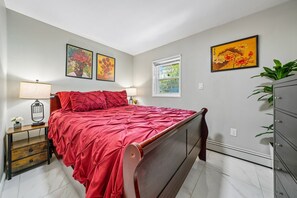 Une chambre à coucher avec un lit en bois, une table de chevet, une commode et une fenêtre donnant sur un beau paysage.