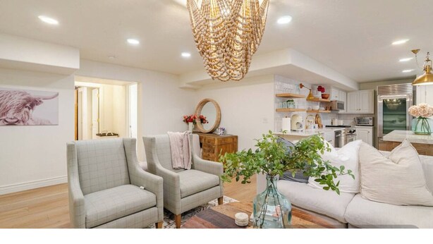 Un salon moderne avec deux fauteuils, un canapé, une plante décorative et, au fond, un coin cuisine.