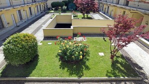 A courtyard with a central garden, surrounded by yellow buildings with balconies. - Moro 137 Apartment Navigli  (MILANO)