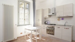 A modern kitchen with white cabinets, a gas stove, and a built-in oven. - Moro 137 Apartment Navigli  (MILANO)