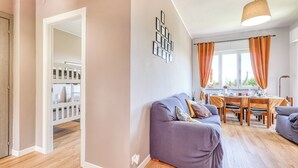 A modern living room with a grey sofa, a dining table with orange curtains, and a staircase leading to a balcony. - Sea Garden - T6 with parking, Ceriale, Italy (Ceriale)