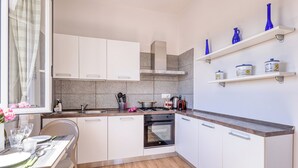 A modern kitchen with white cabinets, a wooden countertop, and a dining area with a table set for two. - Sea Garden - T6 with parking, Ceriale, Italy (Ceriale)