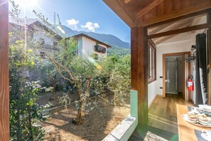 Habitación con vista a un paisaje montañoso, techo de madera y comedor con mesa lista para dos.