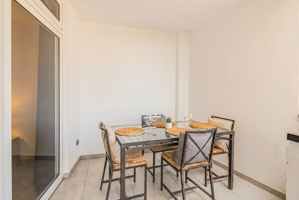 A dining area with a glass table, woven chairs, and a small potted plant.