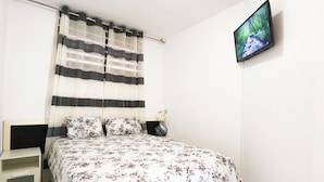 A bedroom with a bed, a nightstand, a TV, and a window with curtains. - Cura Marina Seafront Playa del Cura (Mogán)