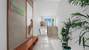Een hotel lobby met een trap, een bank en potplanten.