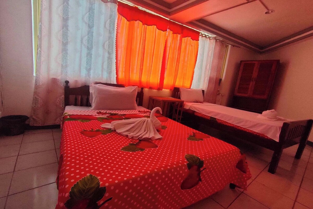 A bedroom with a bed, a small table, a chair, and a cabinet.
