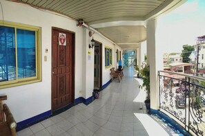 A covered corridor with a wooden door, a window, and a balcony with a railing. - Istroberi Inn By Zuzu (Puerto Princesa)