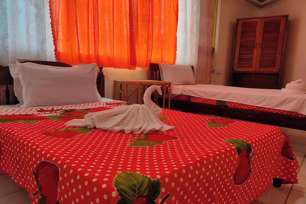 A hotel room with two beds, a wooden wardrobe, and a small table.