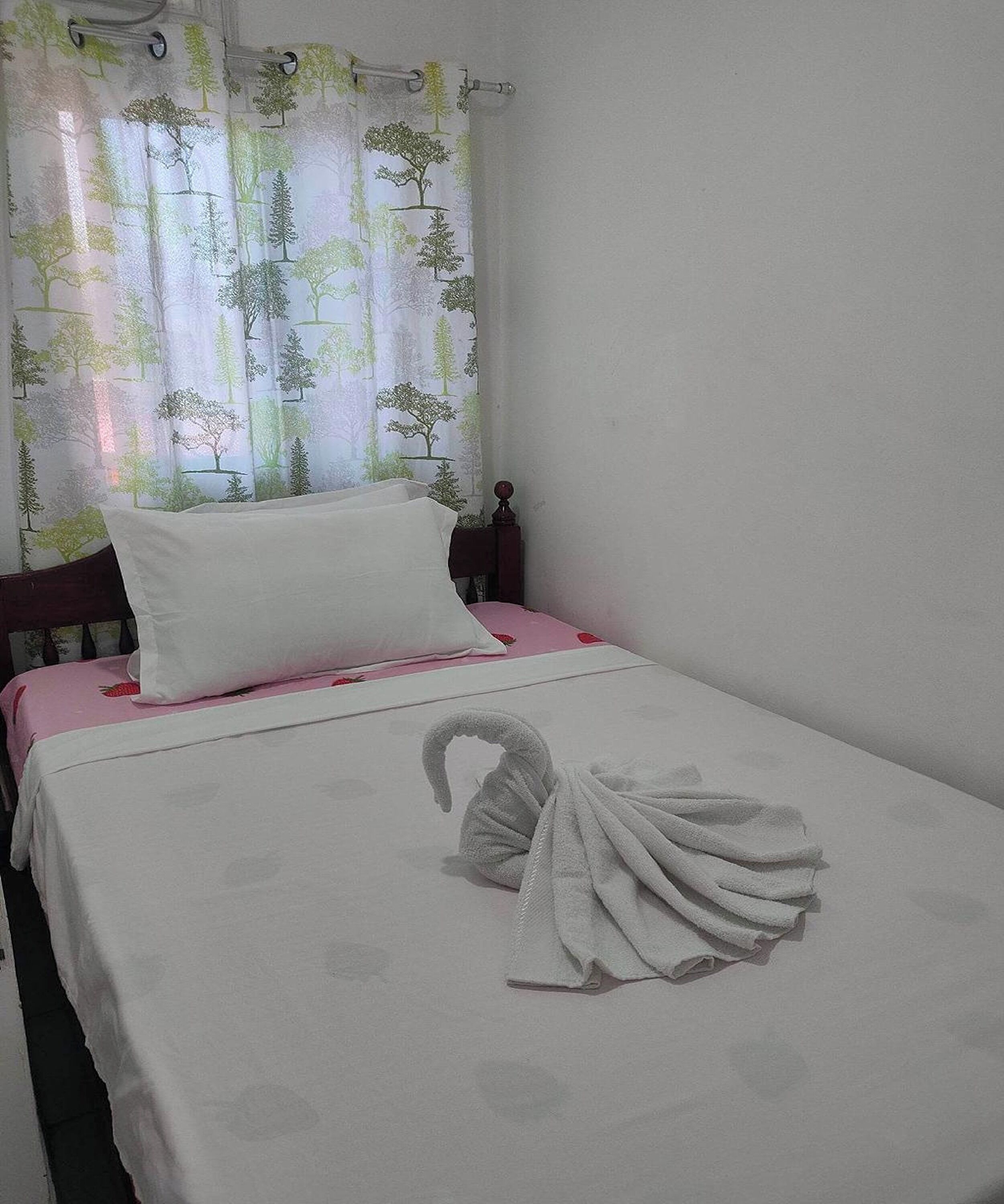 A neatly made bed with a white sheet and a decorative swan towel.
