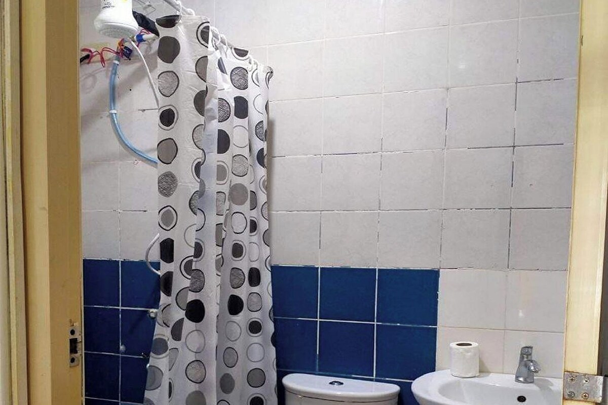 A bathroom with a toilet, sink, and shower curtain.