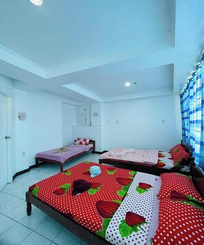 A room with three beds, each with a strawberry-themed bedspread. There is a small table and a chair in the center of the room. - Istroberi Inn By Zuzu (Puerto Princesa)