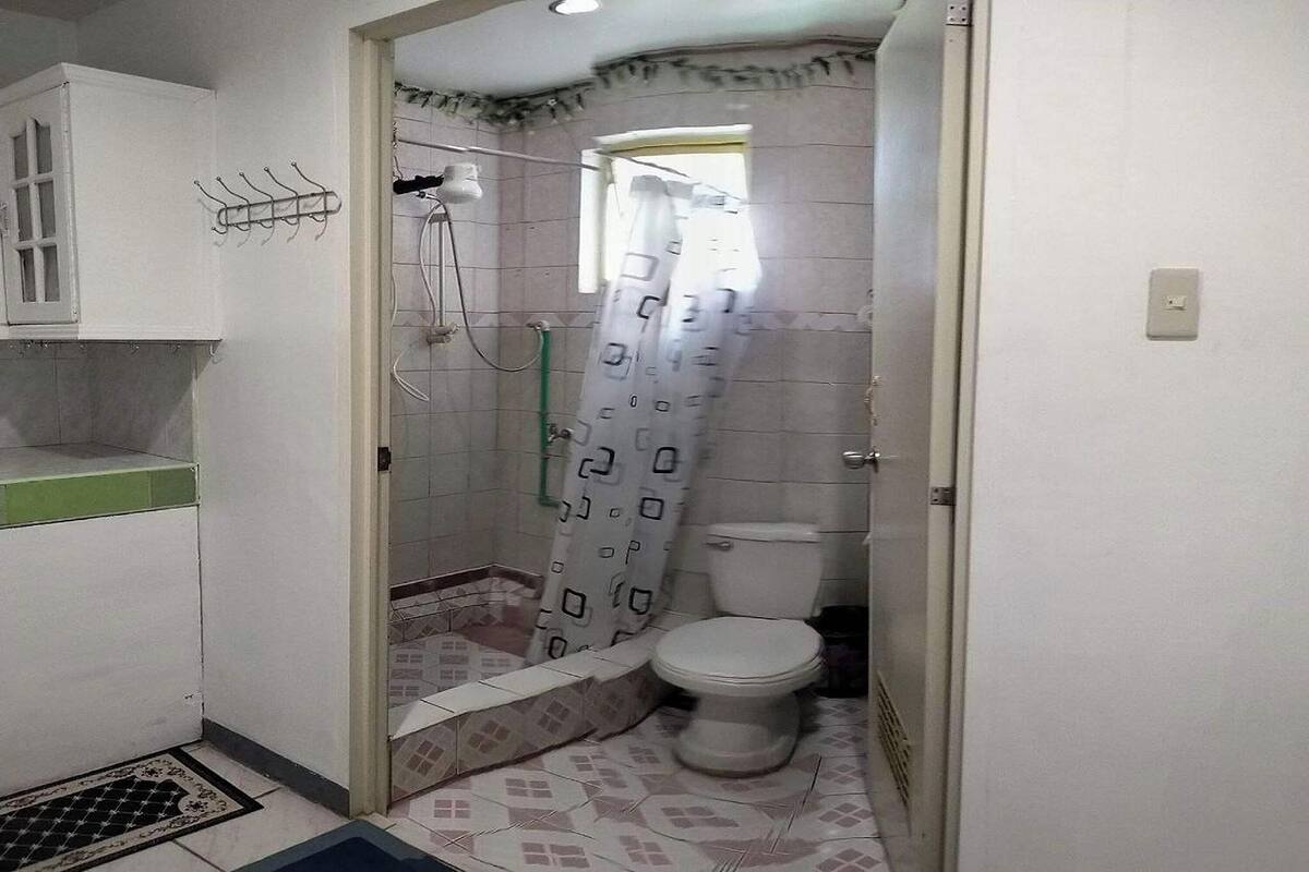 A small bathroom with a toilet, shower, and sink.