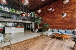 A modern lobby with a reception desk, seating area, and wooden walls.
