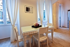 Un coin repas avec une table en verre, des chaises blanches et un plateau avec des bougies.