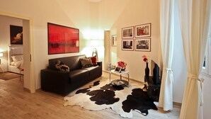Een moderne woonkamer met een zwarte leren bank, een koeienhuidtapijt en een abstract schilderij in het rood.