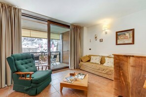 A living room with a green sofa, a wooden coffee table, and a wooden sideboard. - Theo's House with Terrace, Bardonecchia, Italy (Bardonecchia)