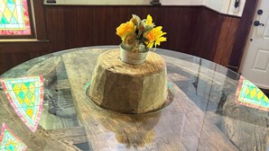 Taula rodona de vidre amb un element decoratiu de fusta i un ram de flors.