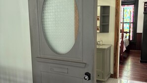 Habitació amb porta corredissa, sòl de fusta i vista a una altra estança amb un rentanet i armaris.