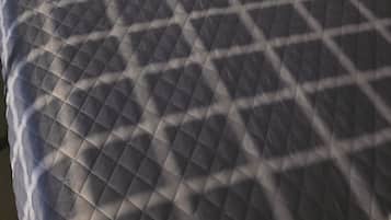 Una cama con un edredón gris acolchado y dos almohadas blancas.