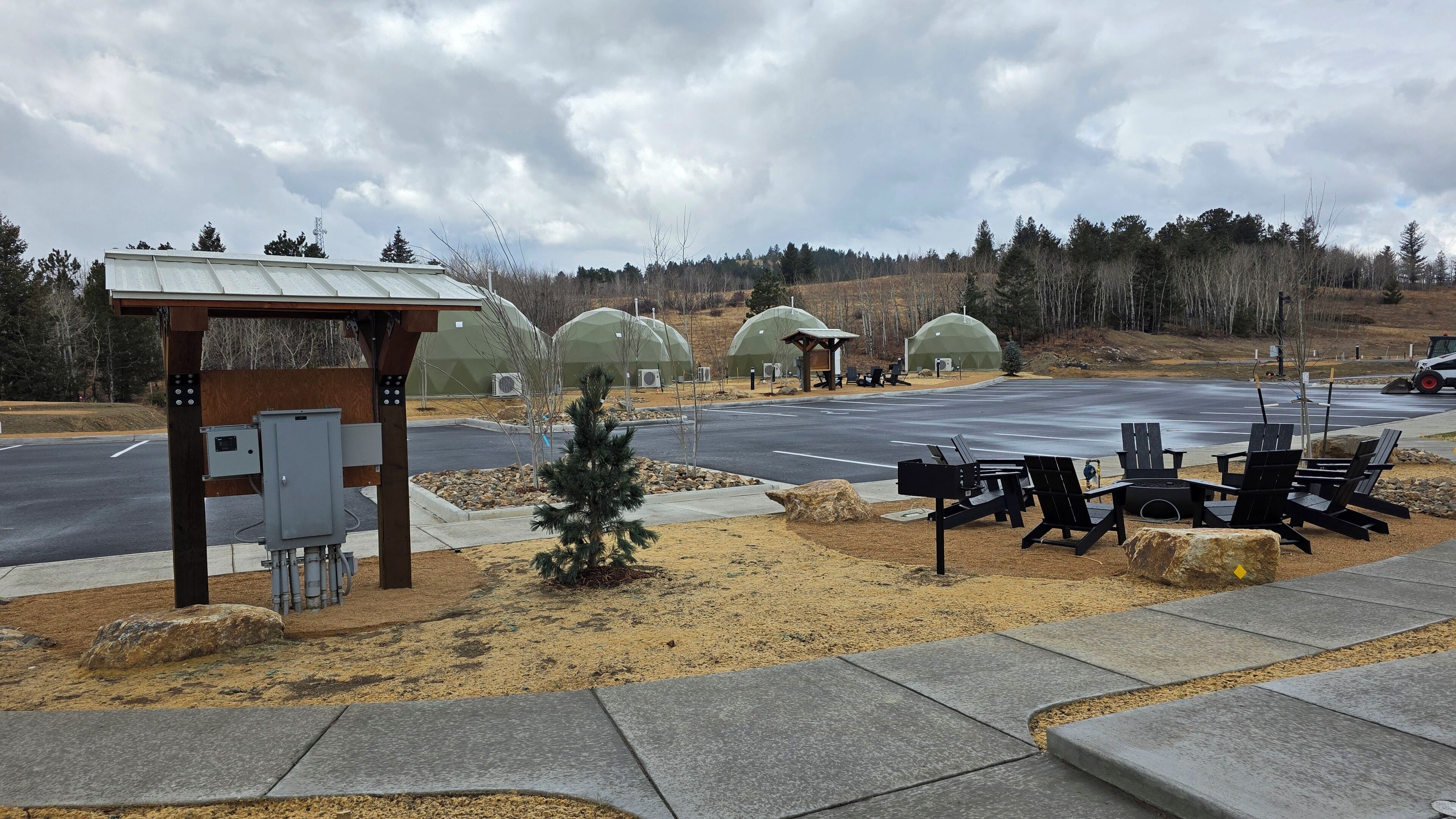 A parking area with outdoor seating and covered structures.