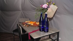 A table with a wooden tray of food, two bottles labeled 'SATAGA', and a bouquet of flowers. - The Nest at Black Hawk (Black Hawk)