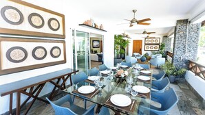 Un coin repas avec une table en verre, des chaises bleues et un mur en pierre.