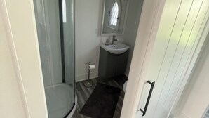 A compact bathroom with a glass shower enclosure, a sink, and a small window above the mirror. - The peaceful oasis

Charming 3-bedroom house with WiFi, AC in welcoming Carroll (Carroll)