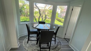 A dining area with a round table and four chairs, a rug, and a view of a garden through large windows. - The peaceful oasis

Charming 3-bedroom house with WiFi, AC in welcoming Carroll (Carroll)