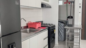 Uma cozinha moderna com eletrodomésticos de aço inoxidável, uma cesta de armazenamento vermelha e uma estante de metal.