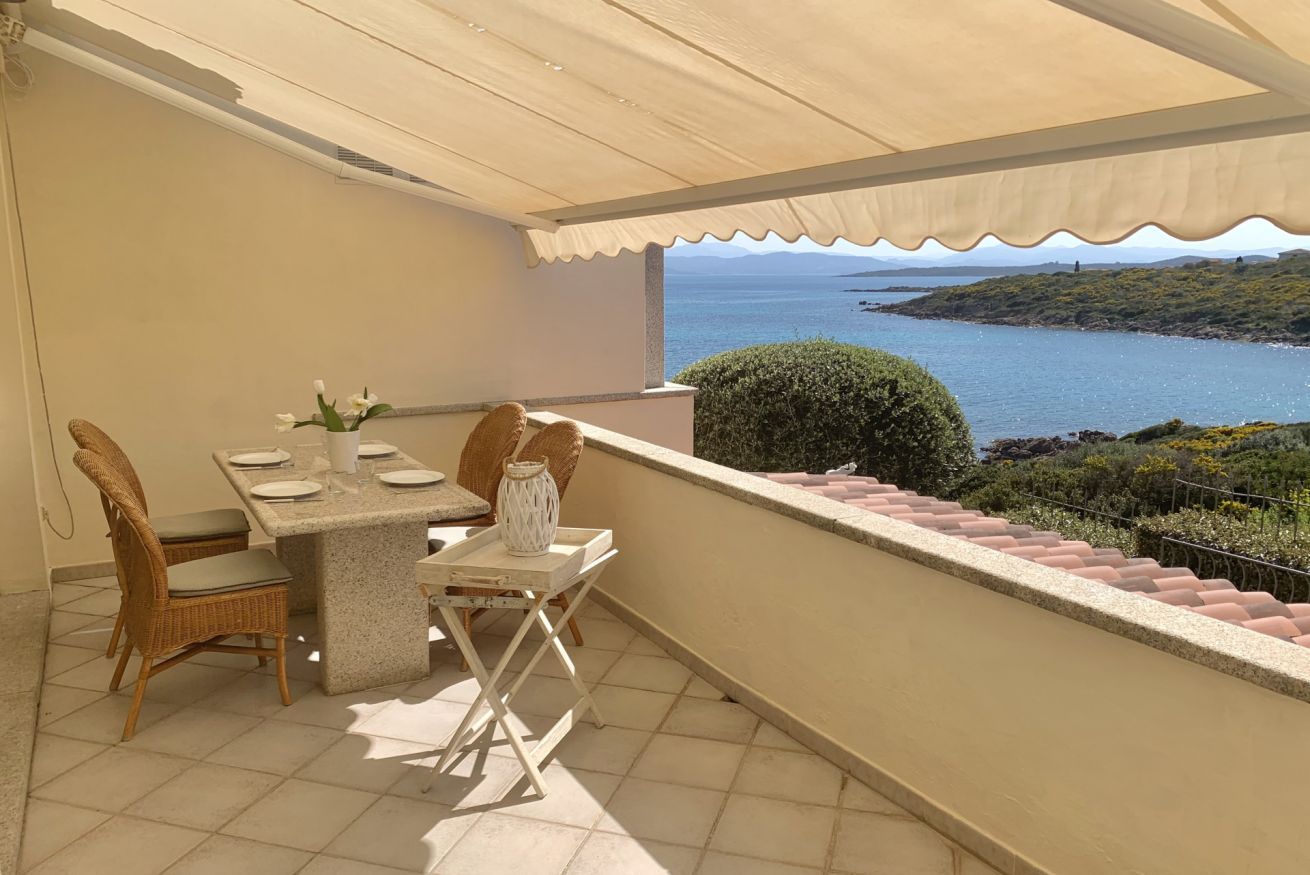 Un balcon avec une table dressée pour deux personnes, offrant une vue sur un paysage côtier.