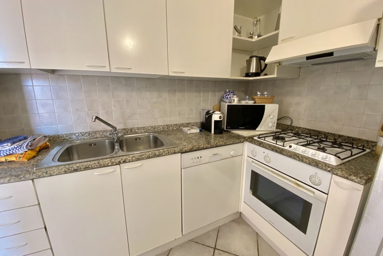 A modern kitchen with white cabinets, a granite countertop, a stainless steel sink, a built-in oven, and a gas stove.