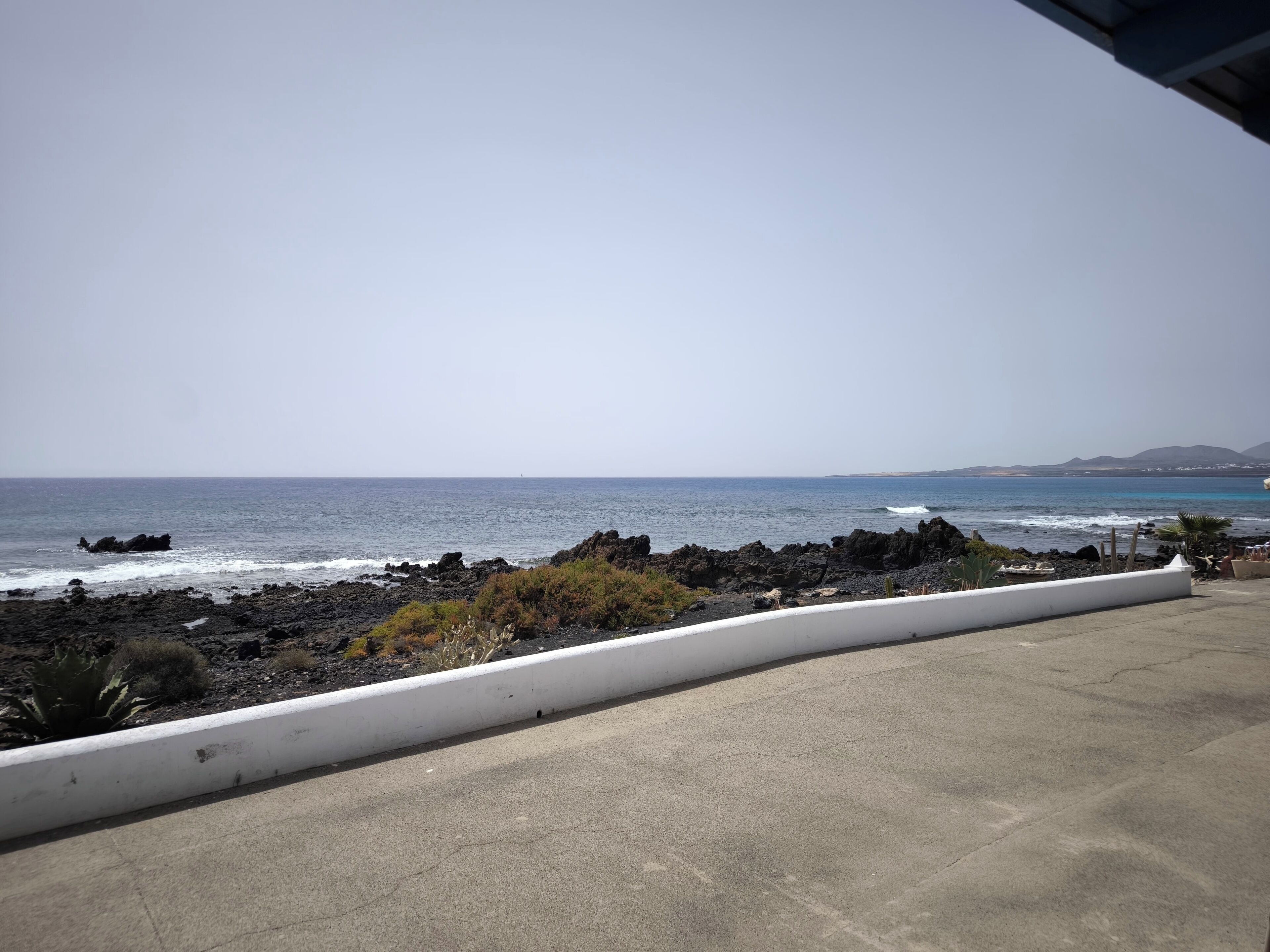 A coastal view with rocky terrain and a clear sky.