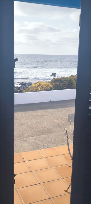 Une vue depuis un balcon doté d’un sol carrelé, d’une chaise et donnant sur la mer.