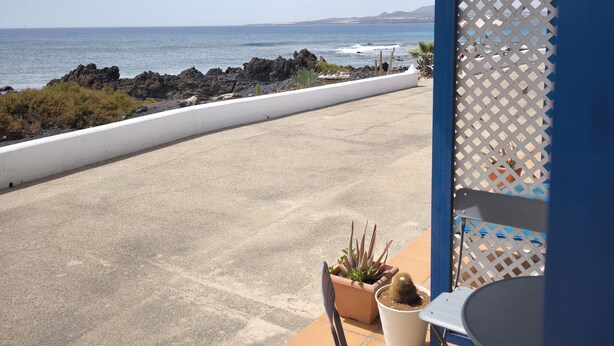Une terrasse avec vue sur l’océan, une balustrade blanche et une table avec des chaises.