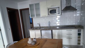 Une cuisine moderne avec des meubles blancs, un lave-vaisselle en acier inoxydable et un four à micro-ondes.