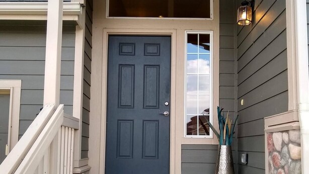 A front entrance with a dark gray door, a small porch area, and a stone accent wall. - Charming 4-bedroom home, High Speed Internet & AC in beautiful Colorado Springs (Colorado Springs)