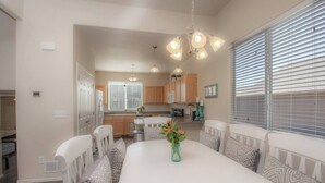 A modern kitchen with wooden cabinets, a white countertop, and a dining area with a white table and patterned chairs. - Charming 4-bedroom home, High Speed Internet & AC in beautiful Colorado Springs (Colorado Springs)