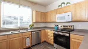 A modern kitchen with wooden cabinets, stainless steel appliances, a microwave, and a dishwasher. - Charming 4-bedroom home, High Speed Internet & AC in beautiful Colorado Springs (Colorado Springs)