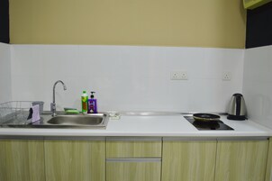 A kitchen with a sink, a kettle, and a stove.