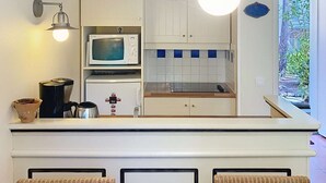 Une cuisine compacte équipée d’un four à micro-ondes, d’une machine à café et d’un luminaire suspendu.