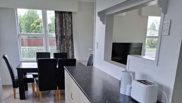 A compact kitchen with a dining area, a built-in oven, a microwave, and a toaster. - 3 Bedroom House A 3 Frank St (Rotorua)
