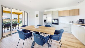 Eine moderne Küche mit weißen Schränken, einem Edelstahlkühlschrank und einer Kaffeemaschine.