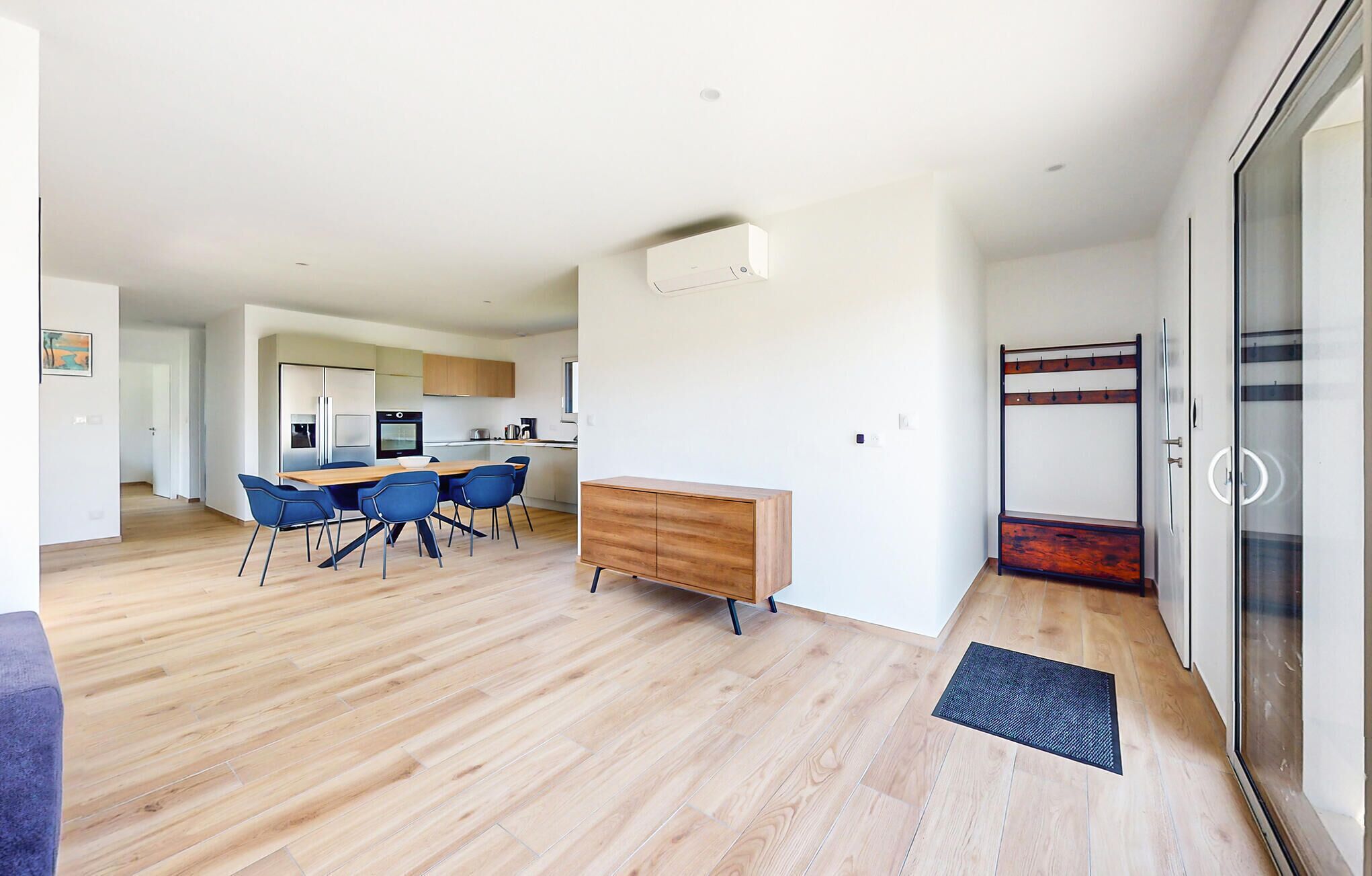 Un appartement moderne comprenant un coin repas, une kitchenette et une porte vitrée donnant sur un balcon.