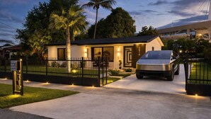 Ein modernes Haus mit Auffahrt, einem Auto und einer Palme.