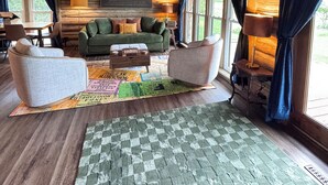 Interior acogedor de una cabaña con techo de madera, un sofá verde, una mesita de centro y una alfombra estampada.