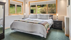 A bedroom with a large bed, two bedside tables, a mirror, and windows with blinds. - Estes Park Retreat w/ Views, Heated Pool, Minutes to Town (Estes Park)